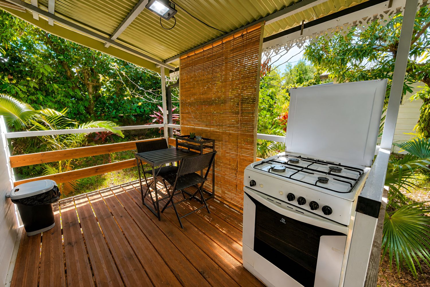 Terrasse privée couverte avec gazinière, table et vue sur le jardin