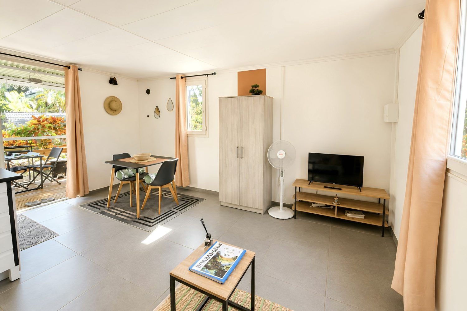 Intérieur lumineux d'un bungalow avec télévision, table basse et coin repas